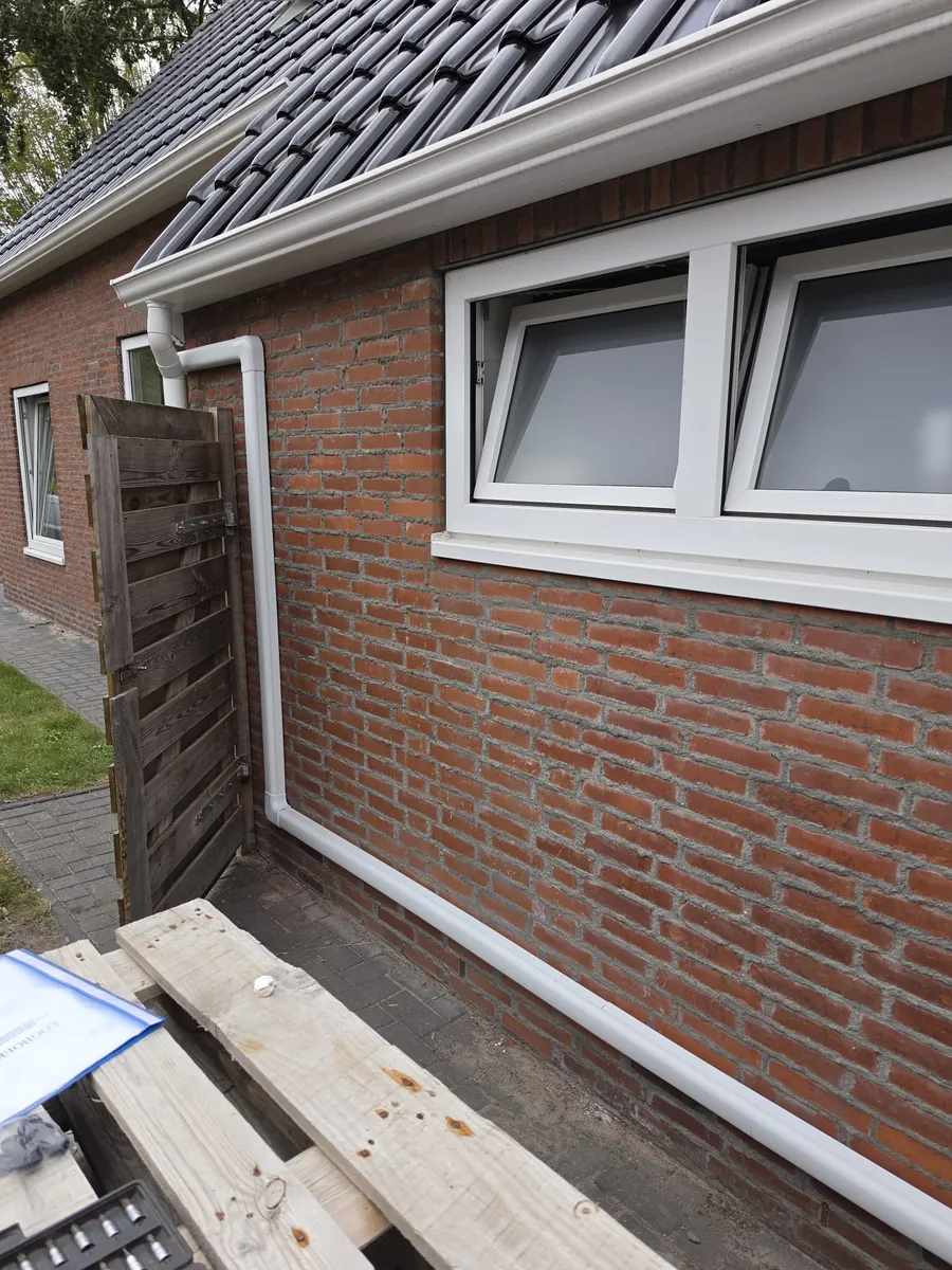 Witte leidinggoten van de multisplit-airco langs de gevel
